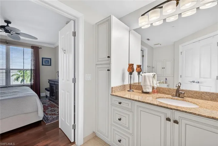 Ensuite bathroom featuring vanity, ceiling fan, and light wood-style flooring