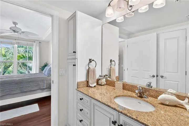 Bathroom featuring ensuite bath, vanity, dark wood-type flooring, and a ceiling fan