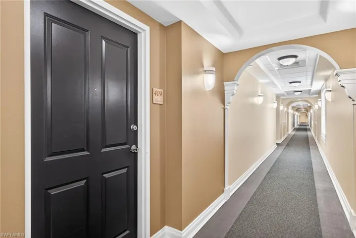 Hallway with dark carpet and arched walkways
