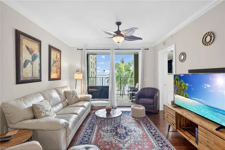 Living area with ornamental molding, ceiling fan, and dark wood-style flooring
