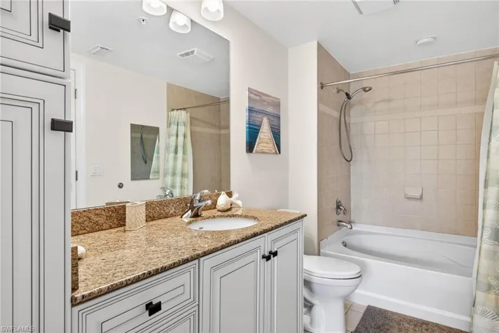 Bathroom with vanity, shower / tub combo, and tile patterned flooring