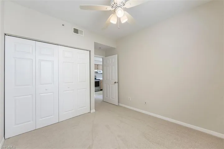 Unfurnished bedroom featuring light colored carpet, a closet, and ceiling fan