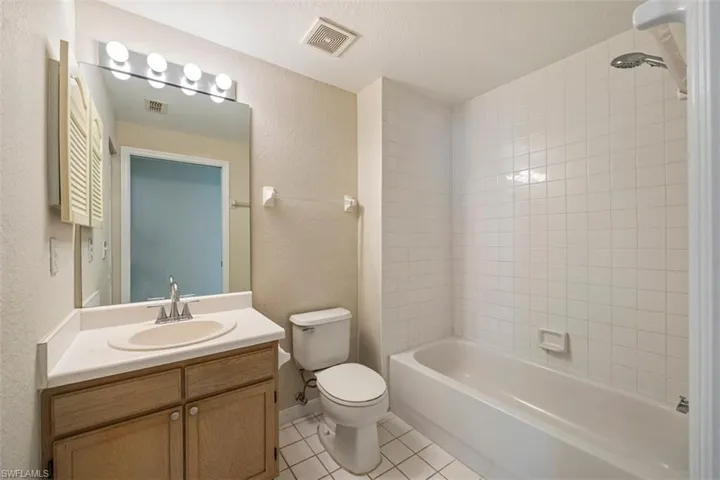 Full bath featuring tile patterned flooring, vanity, shower / bathtub combination, and a textured wall