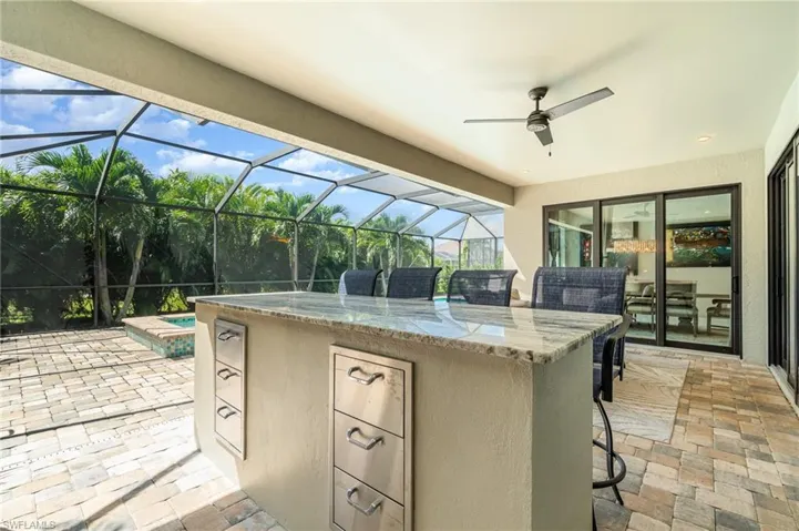 View of lanai with screen enclosure, an outdoor bar, and ceiling fan
