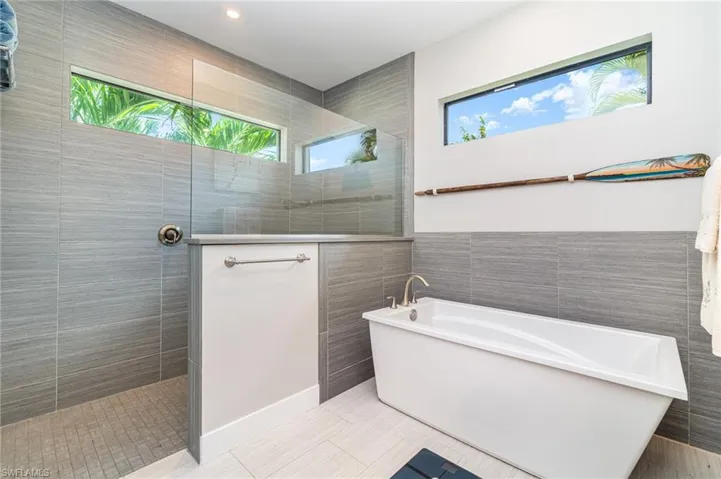 Primary bathroom featuring independent shower and bath, tile walls
