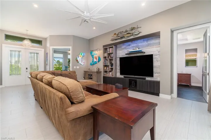Living room with ceiling fan with notable chandelier and french doors