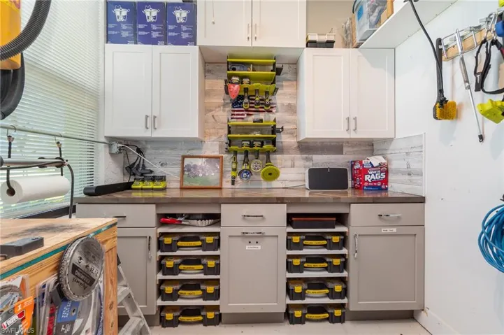 Garage work area featuring backsplash, butcher block countertops, and cabinets