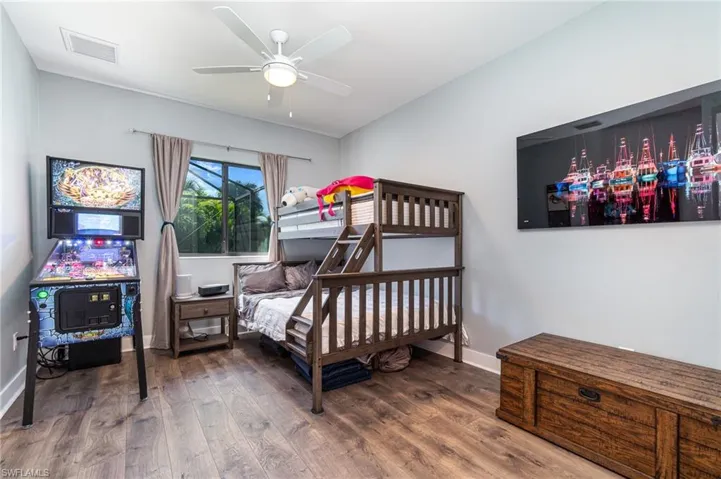 Guest bedroom featuring wood floors, walk in closet and ceiling fan