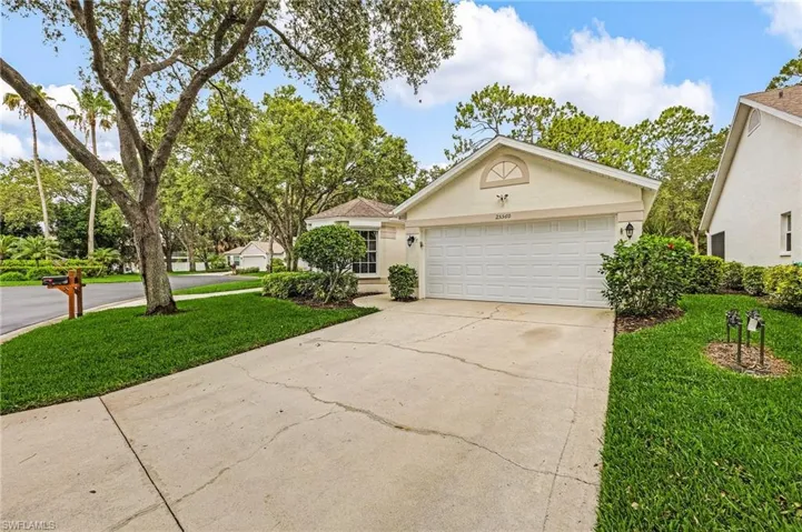 View of front of home with stucco siding, concrete driveway, a front lawn, and a two-car garage