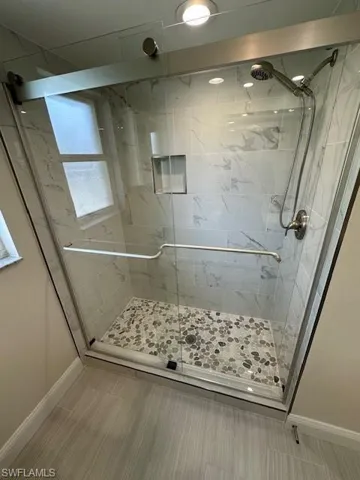 Guest Bathroom with new shower doors, tiled wall and River stone tile floor.