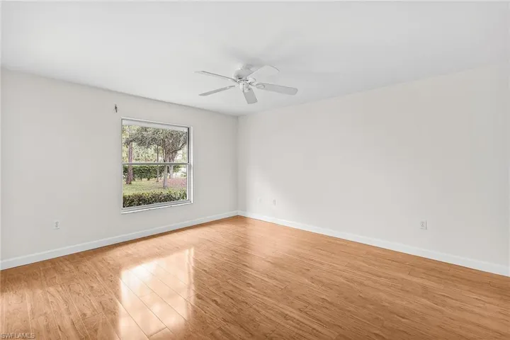 The spacious primary bedroom has been freshly painted and boasts wood finished floors and ceiling fan.