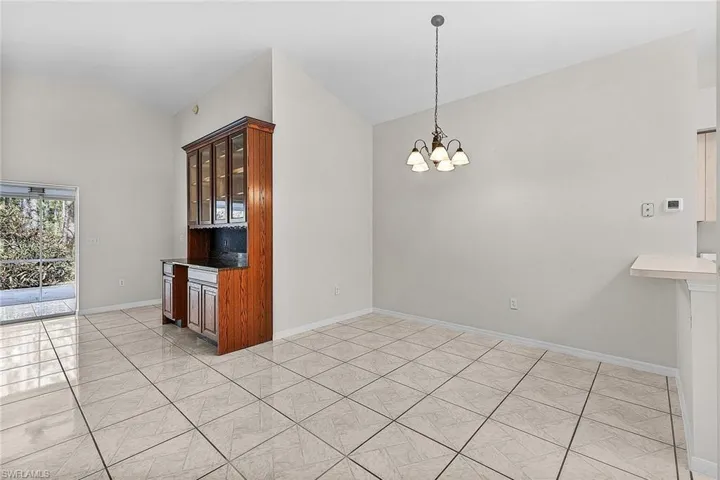The spacious great room features a custom built-in bar with a granite countertop, glass front cabinetry and a cut-out for a beverage/wine fridge, and dining area.