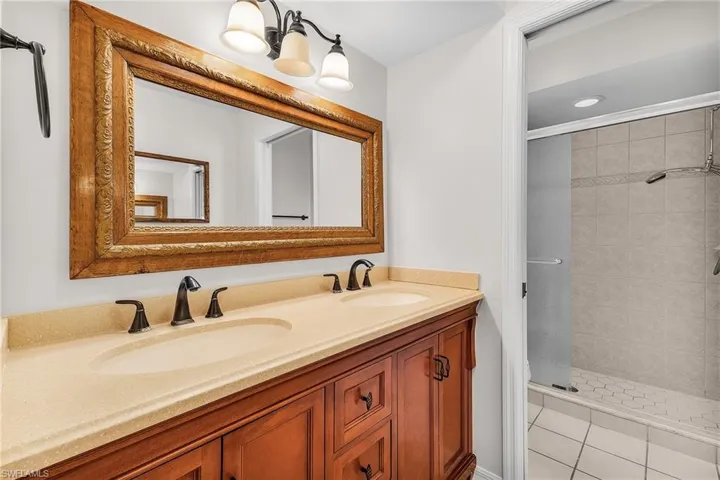 The en-suite primary Bathroom features a wood vanity with dual sinks and solid-surface countertop, and a walk-in shower.