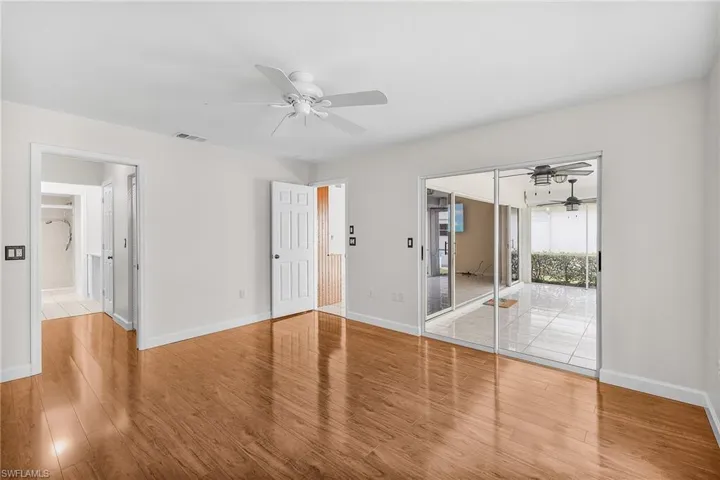 The primary bedroom features wood flooring, an en-suite bathroom, a walk-in closet, a reach-in closet, and sliders that access the lanai.