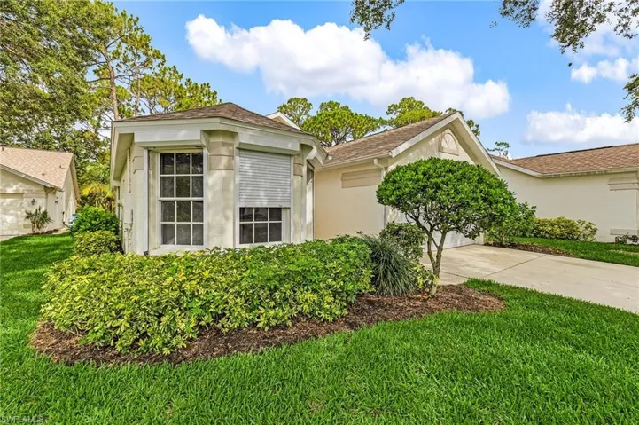 View of front facade featuring stucco siding, a front lawn, and driveway