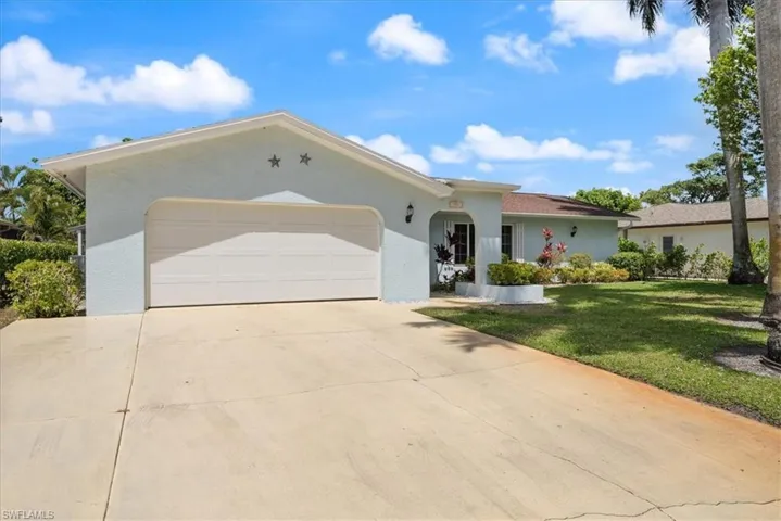 Ranch-style home with concrete driveway, an attached garage, stucco siding, and a front lawn