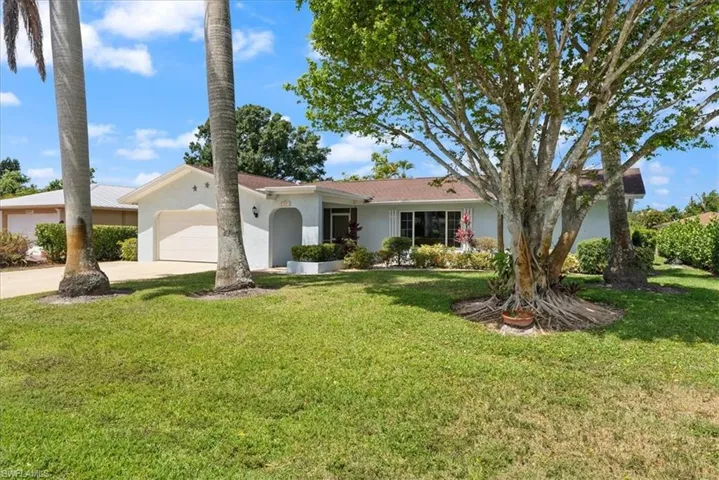 Ranch-style home featuring a front yard, stucco siding, driveway, and a garage