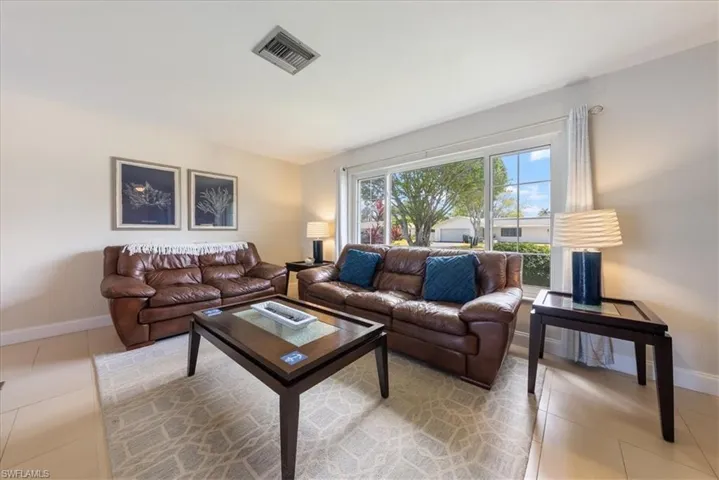 Living area with light tile patterned flooring, baseboards, and visible vents