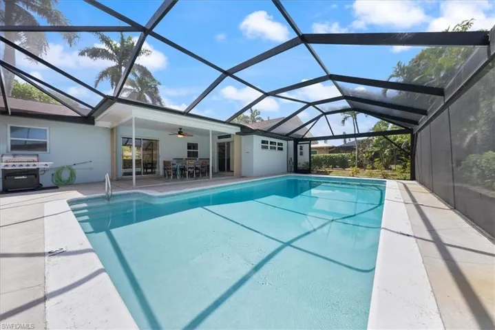 Pool featuring a patio area, area for grilling, glass enclosure, ceiling fan, and outdoor dining area