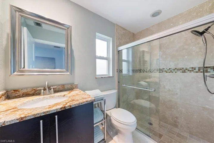 Full bath featuring vanity, toilet, visible vents, and a shower stall