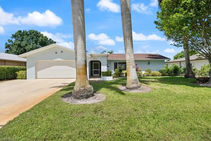 View of front facade featuring concrete driveway, a front yard, stucco siding, and a garage