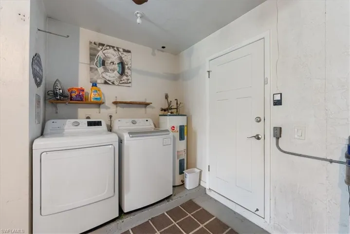 Clothes washing area featuring washer and dryer, electric water heater, and laundry area