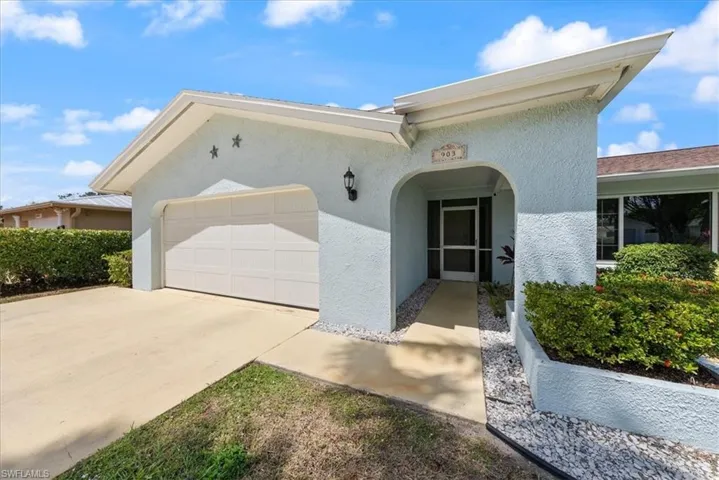 View of front of property with concrete driveway, stucco siding, and an attached garage