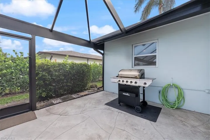 View of patio featuring area for grilling and glass enclosure