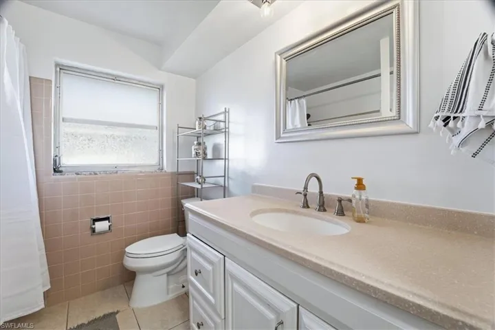 Full bathroom featuring vanity, light tile patterned flooring, and a shower with curtain