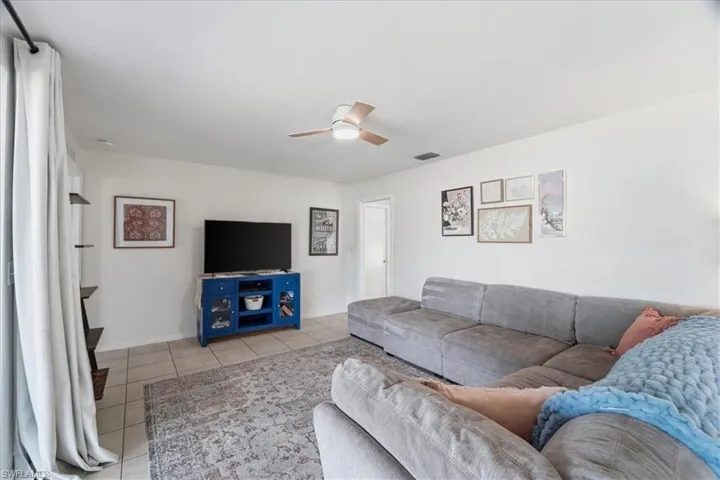 Living room with light tile patterned floors and a ceiling fan