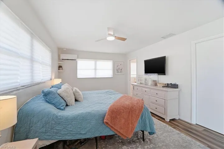 Bedroom featuring light wood-style floors, ceiling fan, and a wall mounted air conditioner