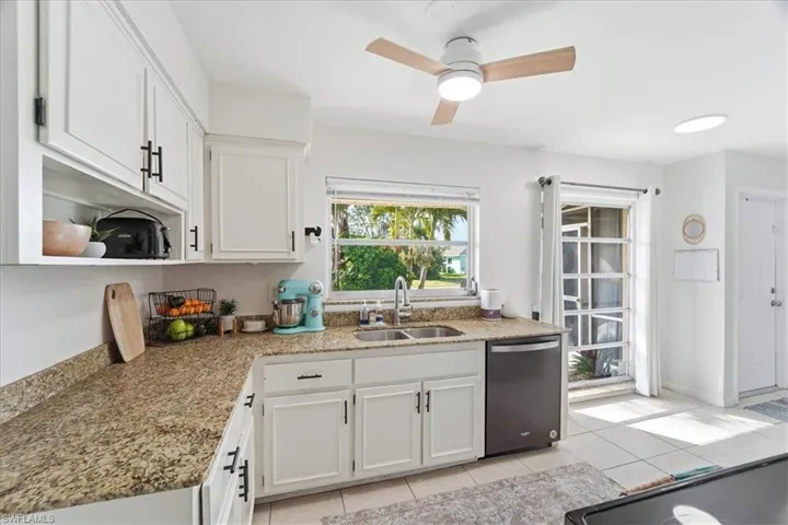 Kitchen with white cabinetry, dishwasher, and light tile patterned flooring