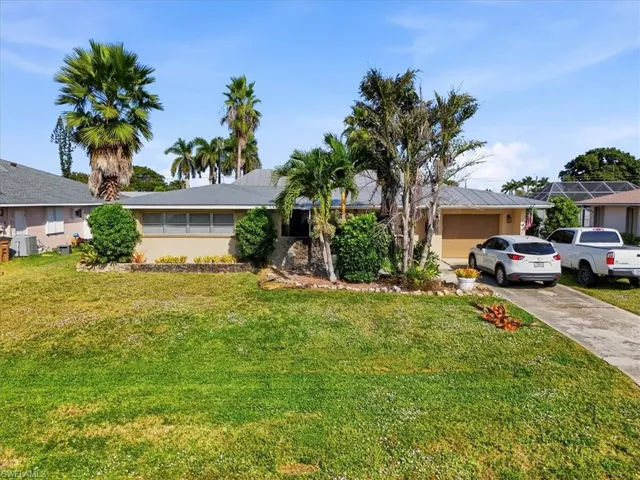 Ranch-style home with a front yard, concrete driveway, and an attached garage