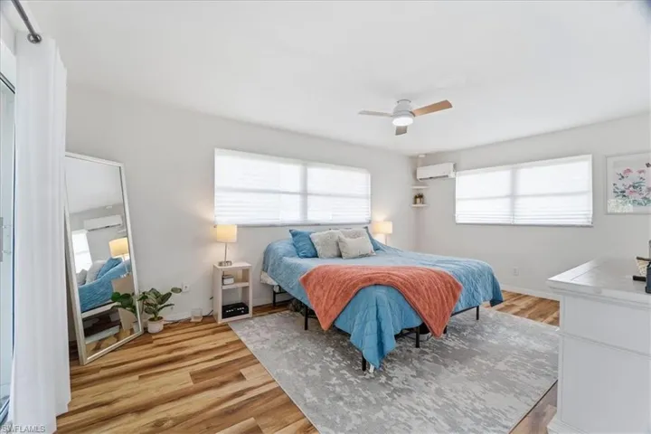 Bedroom featuring light wood-type flooring, ceiling fan, and a wall mounted AC