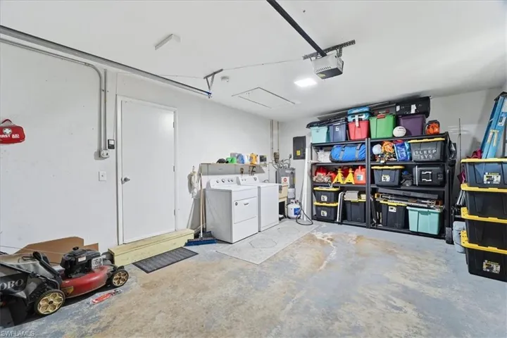 Garage with independent washer and dryer, electric water heater, and a garage door opener