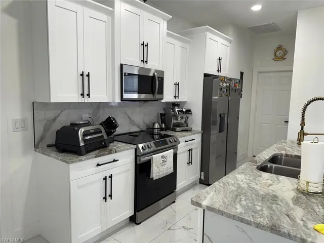 Kitchen featuring visible vents, a sink, white cabinets, appliances with stainless steel finishes, and marble finish floor