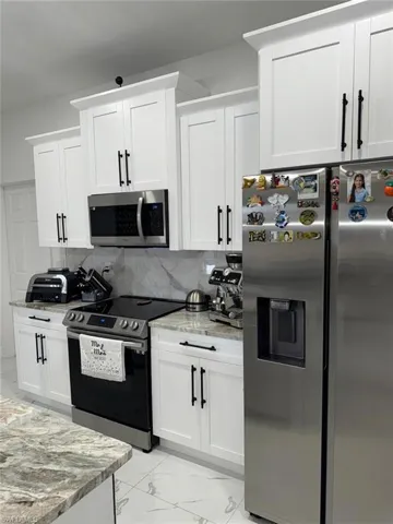 Kitchen featuring tasteful backsplash, marble finish floor, stainless steel appliances, and light stone counters
