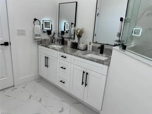 Bathroom with a sink, marble finish floor, double vanity, and a walk in shower