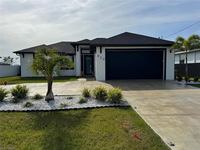 View of front of property with stucco siding, roof with shingles, concrete driveway, a front yard, and an attached garage
