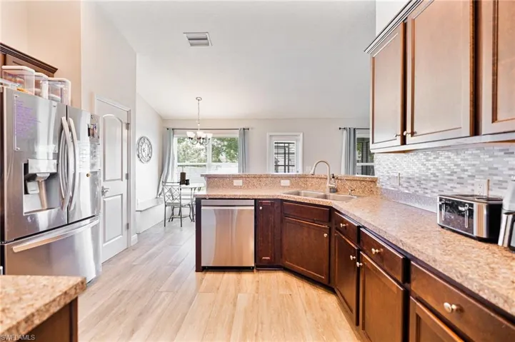Kitchen featuring pendant lighting, sink, appliances with stainless steel finishes, an inviting chandelier, and light wood-type flooring