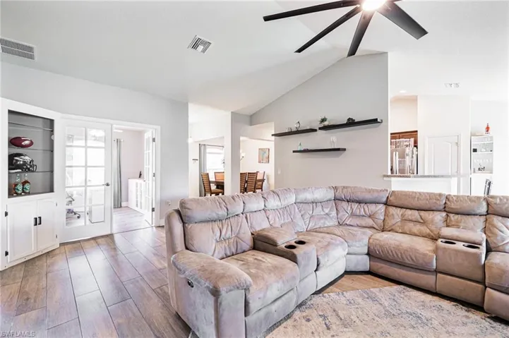 Living room featuring light hardwood / wood-style flooring, lofted ceiling, and ceiling fan