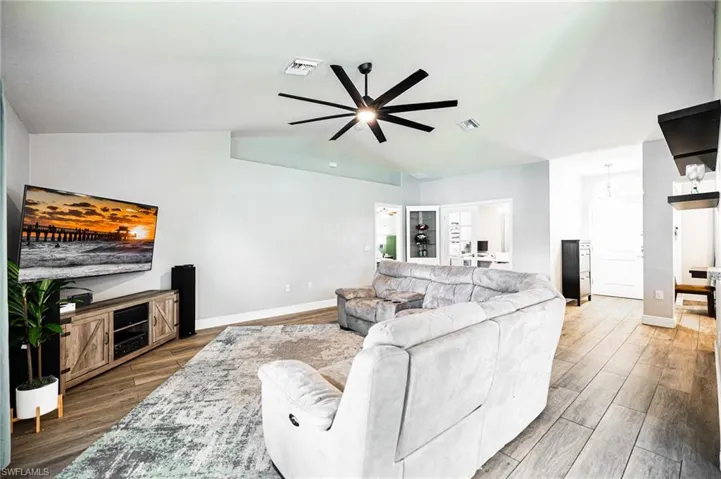 Living room featuring ceiling fan, hardwood / wood-style flooring, and lofted ceiling