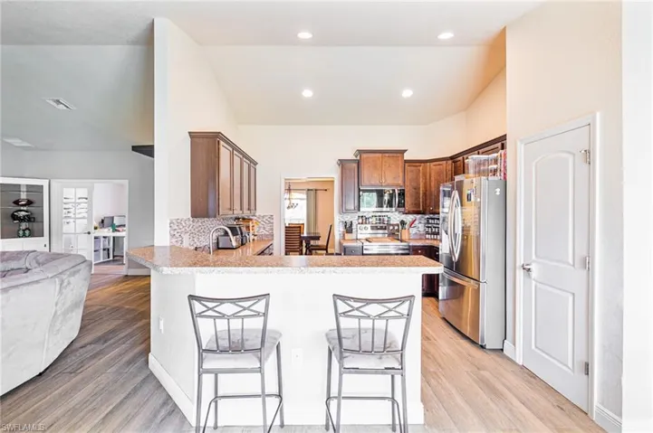 Kitchen featuring stainless steel appliances, kitchen peninsula, decorative backsplash, and light hardwood / wood-style flooring