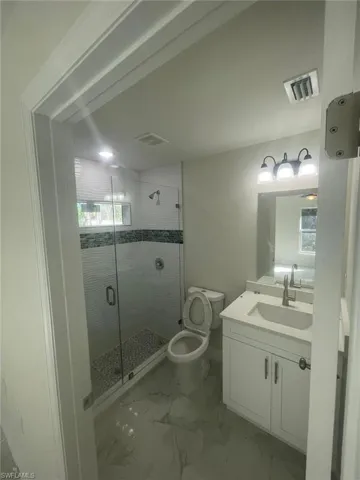 Bathroom featuring vanity, toilet, and a shower with shower door