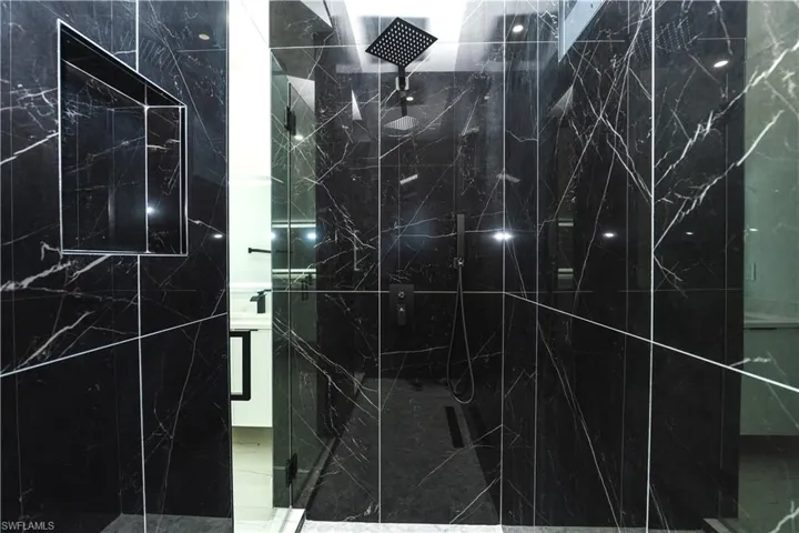 Bathroom view of vanity and a marble finish shower