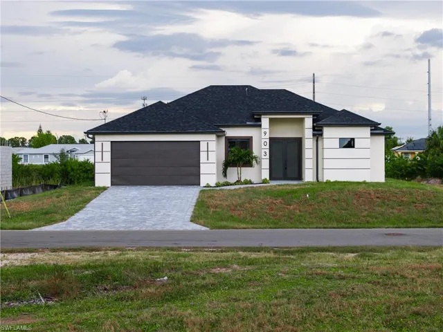 View of front of home with stucco siding, a front yard, a shingled roof, decorative driveway, and a garage