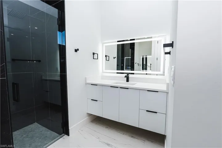 Full bathroom with vanity, a marble finish shower, and light marble finish flooring