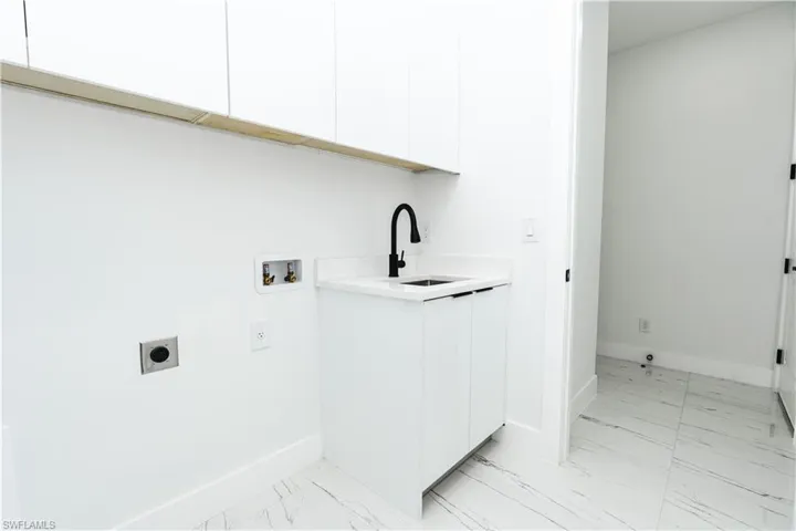 Laundry area featuring light marble finish floors, cabinet space, hookup for an electric dryer, and washer hookup