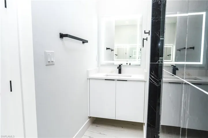 Full bathroom featuring vanity, a shower stall, and light marble finish flooring