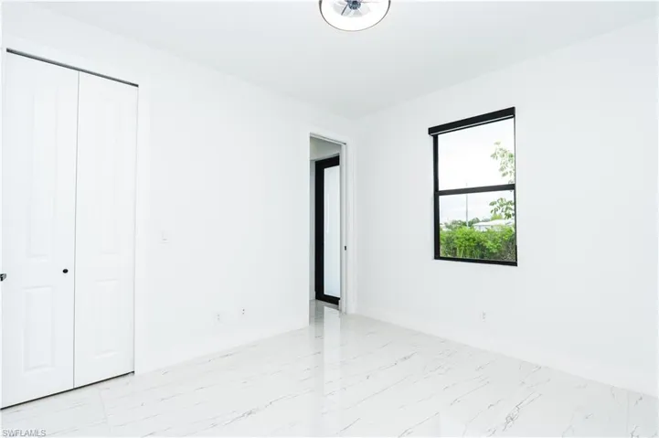 Unfurnished bedroom featuring light marble finish floors and a closet
